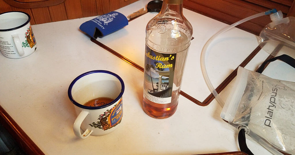 Nearly empty bottle of Sebastian's Rum with a Pusser's tin cup next to it on the galley counter.