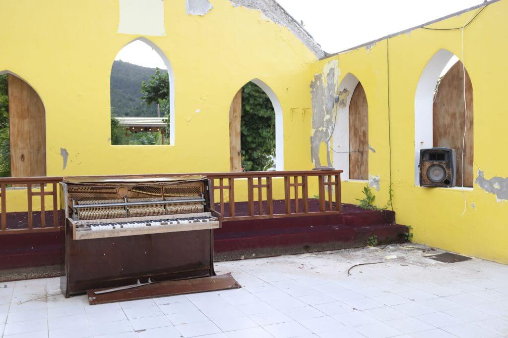 yellow church walls with no roof and piano and altar