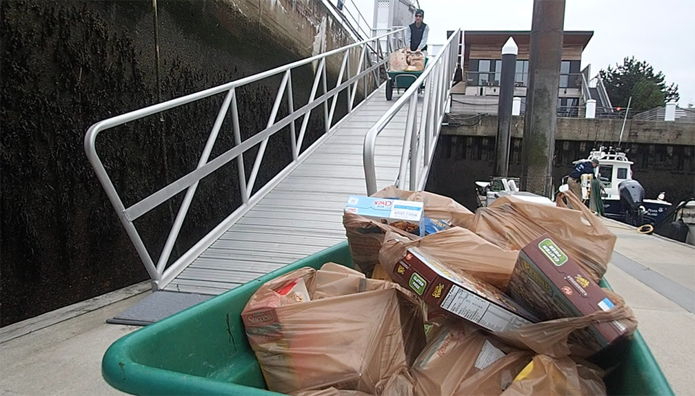 Person coming down a gangplank with a cart and provisions