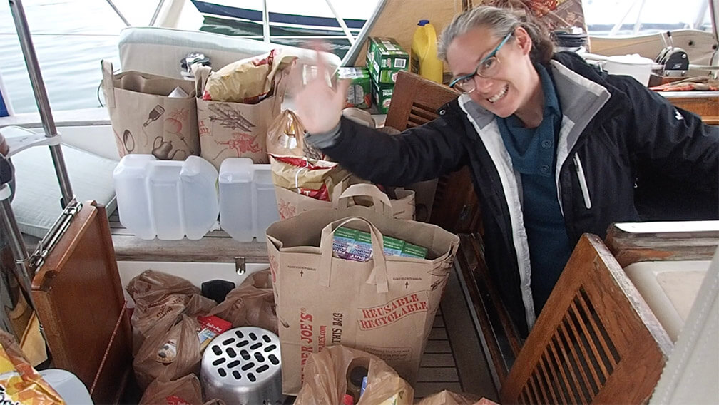 woman in the cockpit of a boat surrounded by groceries