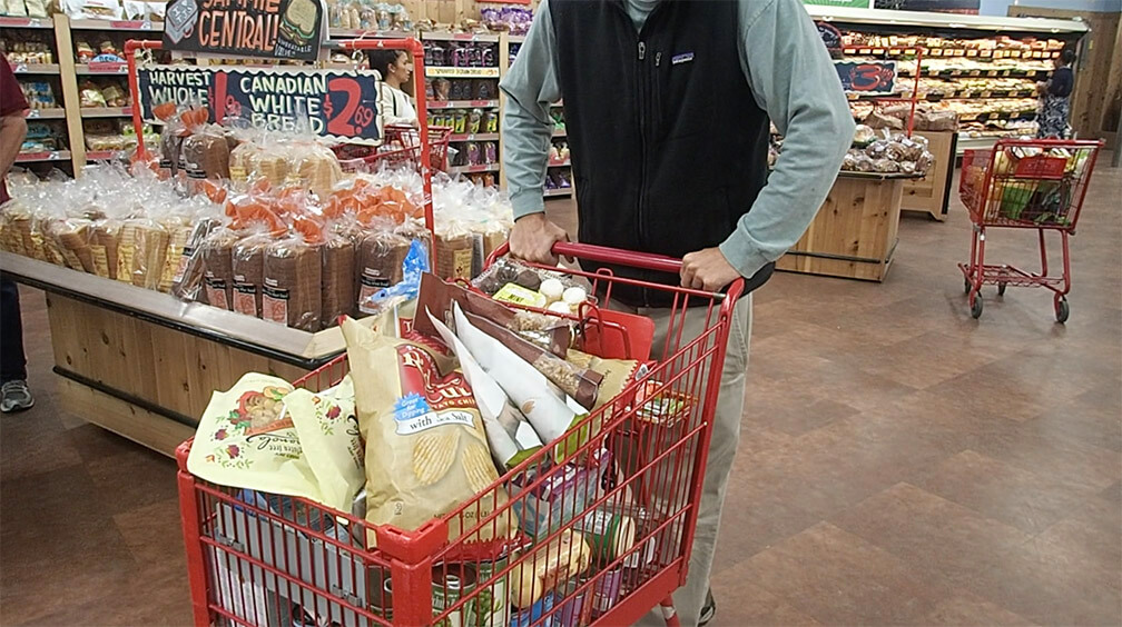 man with a shopping cart full of groceries at Trader Joe's