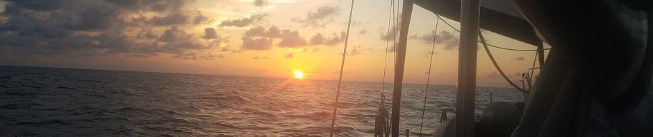 sunset from port side of a sailboat with the sails out